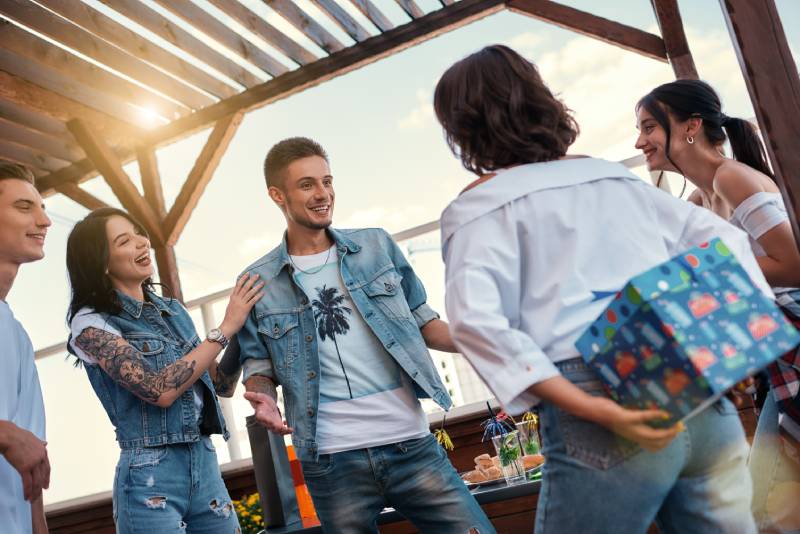 group of friends outside smiling hiding a gift