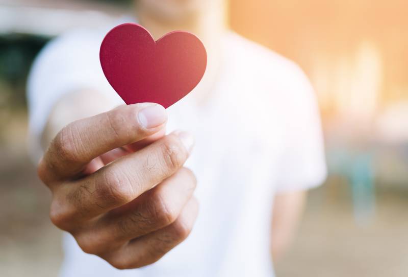 man holiding cut out paper heart