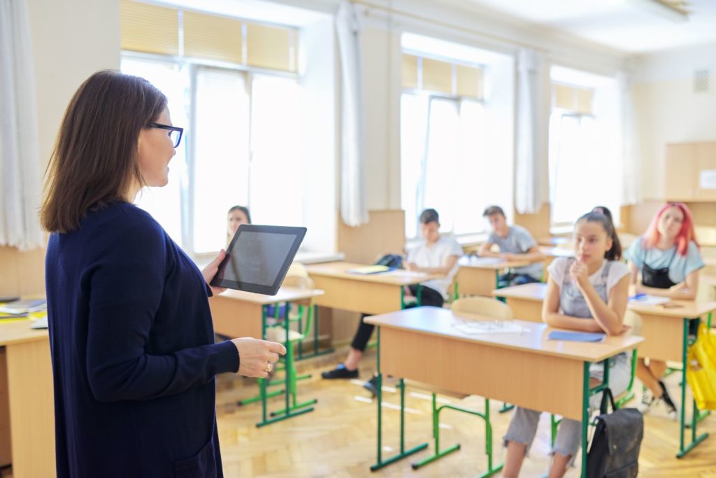 Portrait of talking middle-aged teacher woman in classroom with students